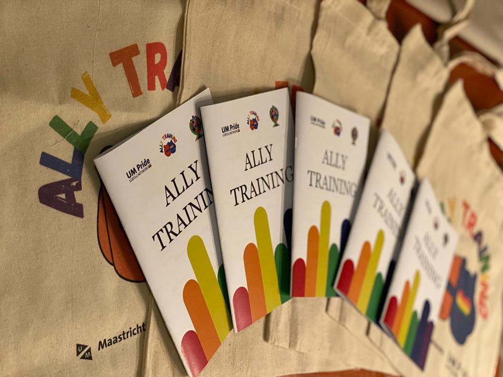 Tote bags and brochures with the text: Ally training. In rainbow text: ally training. Two colourful teddy bears hugging each other. 