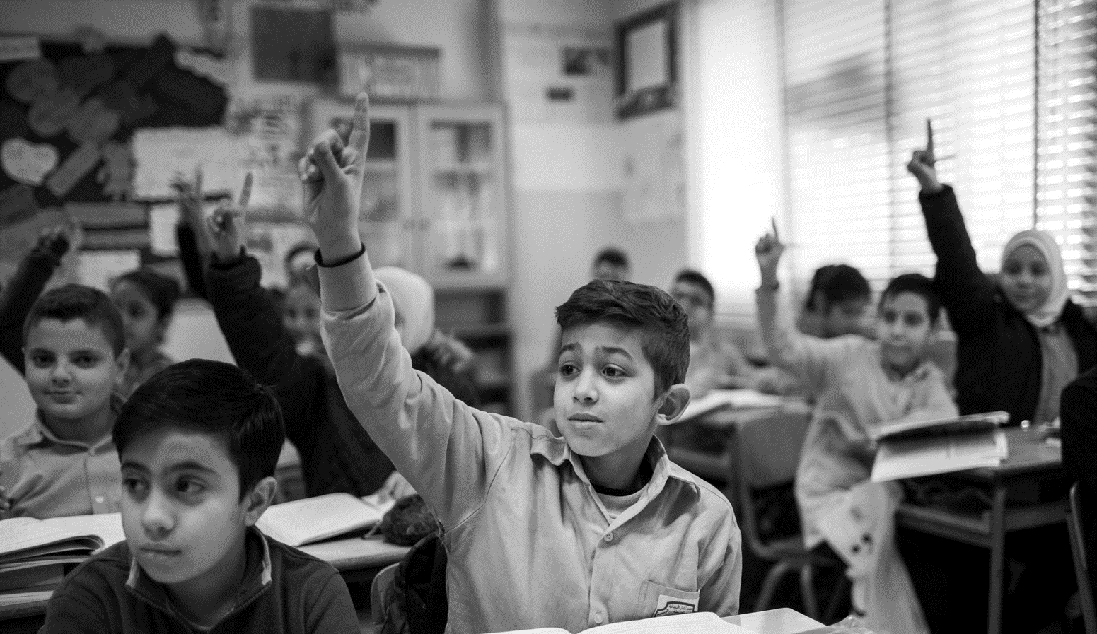 A boy raising his hand in a classroom