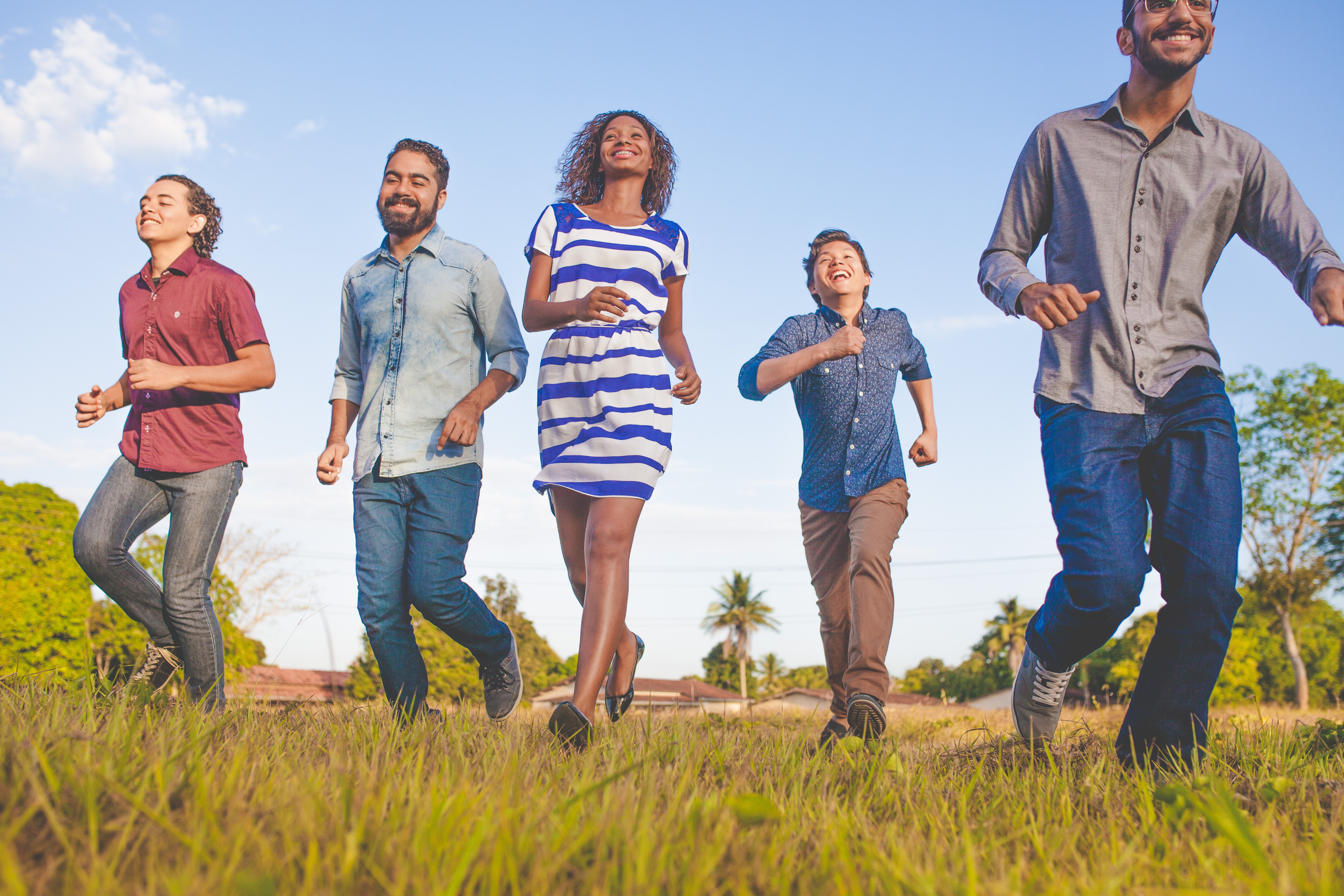 5 people smiling and walking on the grass