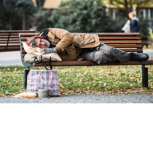 Homeless man lying on a bench in the park