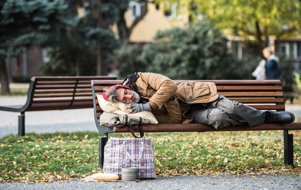 Homeless man lying on a bench in the park