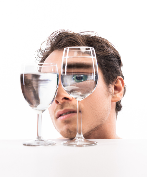 Man looking at wine glasses filled with water