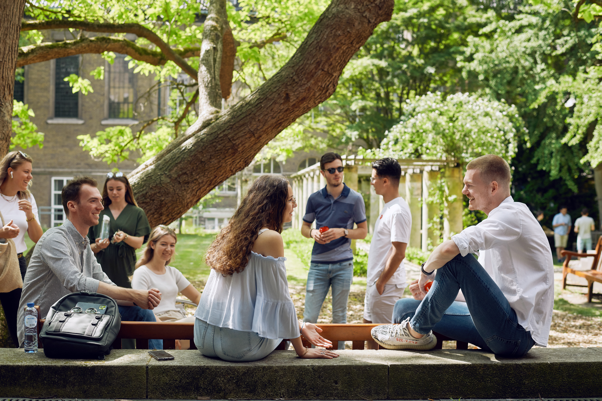 Studenten zitten op een zomerse dag in de tuin van de Faculteit der Rechtsgeleerdheid