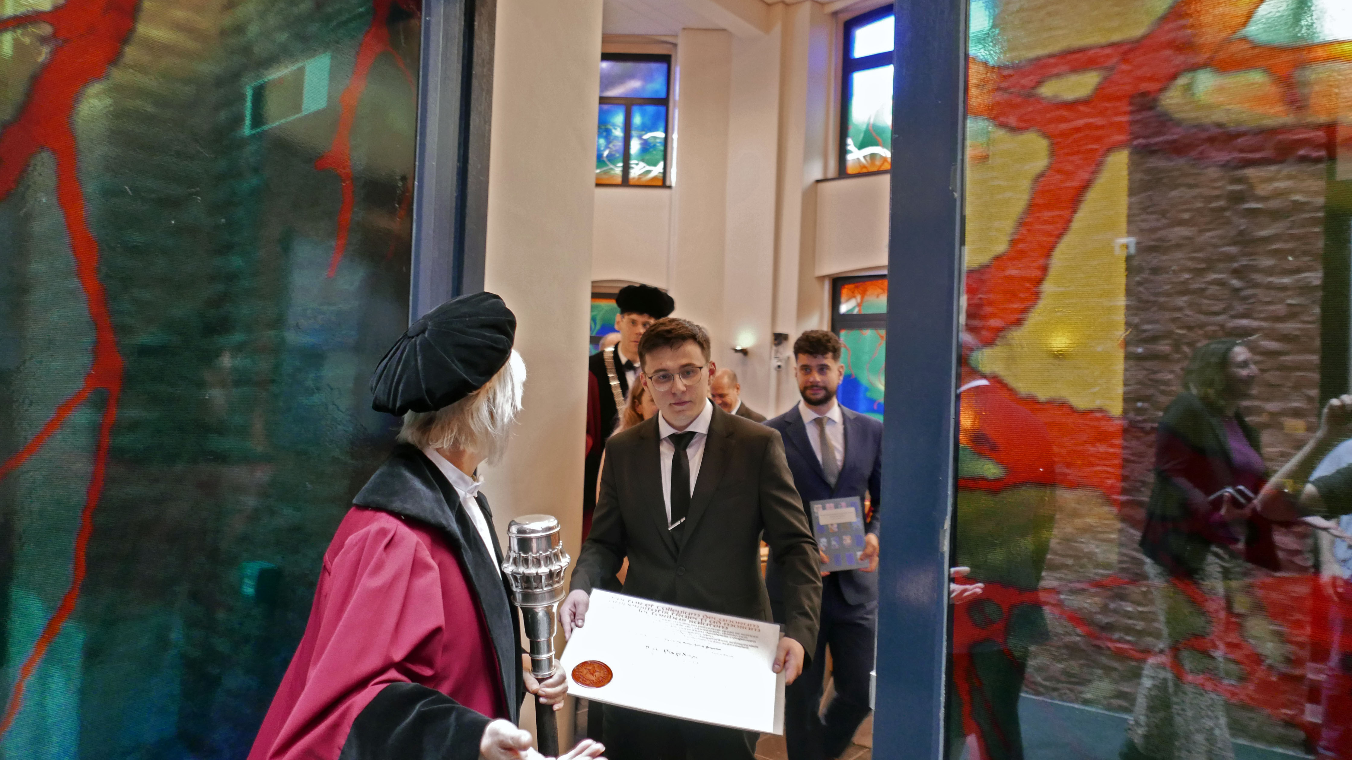 Bulat Khaertdinov holds his PhD-diploma while walking out of the auditorium
