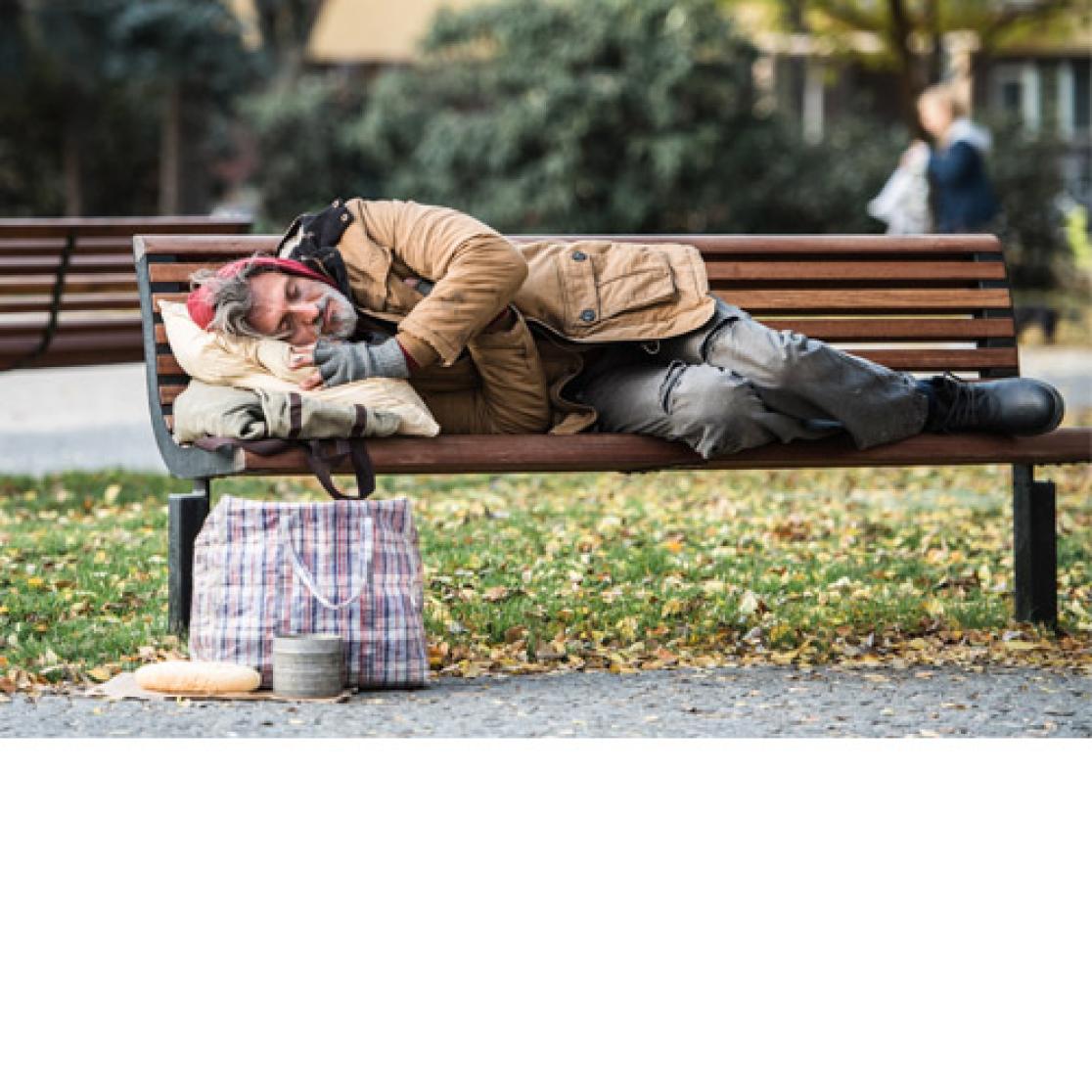 Homeless man lying on a bench in the park