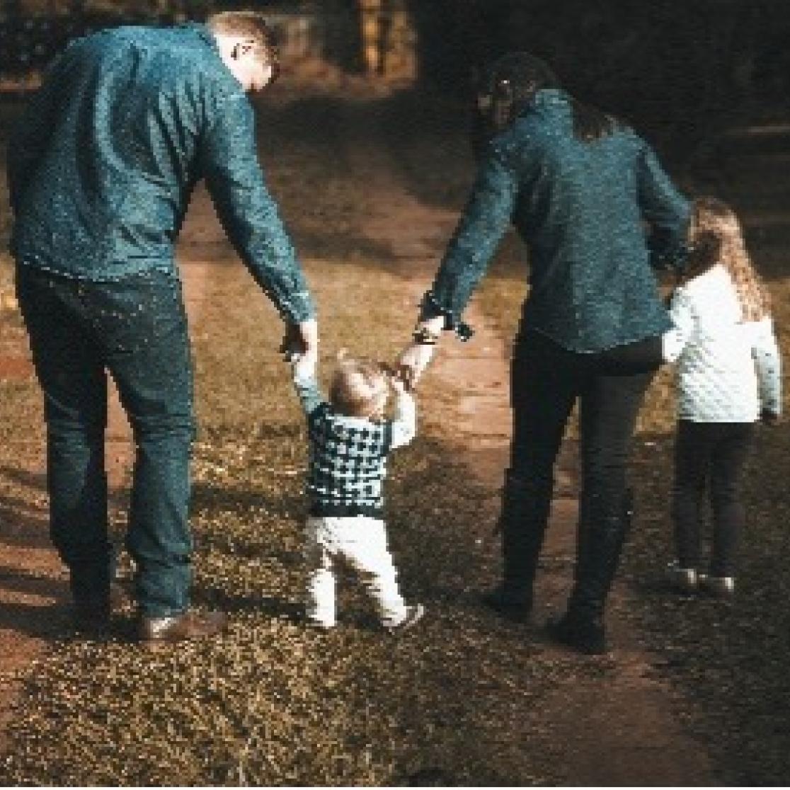 A couple walking with a child in the middle, holding hands