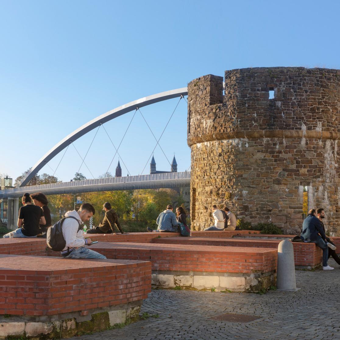 People sitting beside the Maas at Ceramique