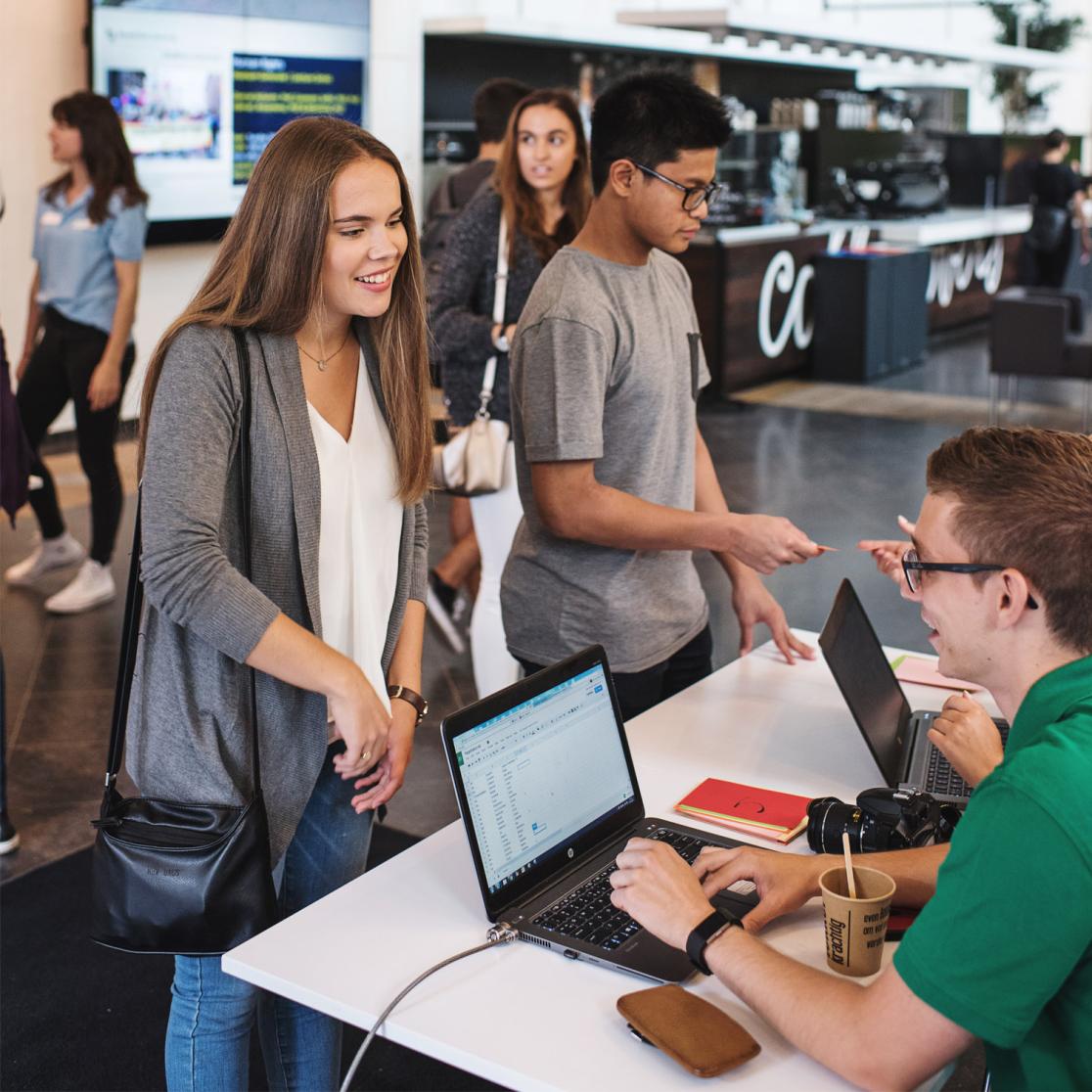 Students registering at a check-in table with laptops