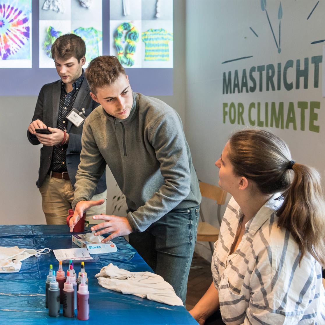A 'maastricht for climate' stand with 3 people busy