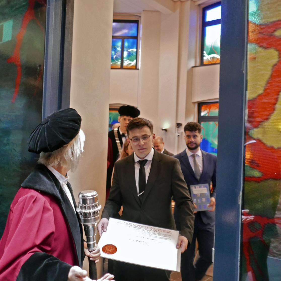 Bulat Khaertdinov holds his PhD-diploma while walking out of the auditorium