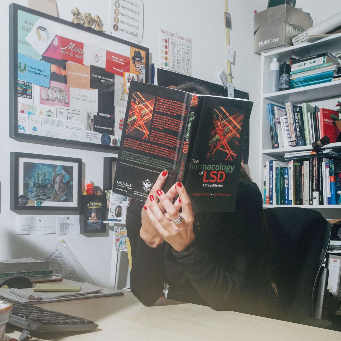 Kim Kuypers at her desk with a book infront of her face