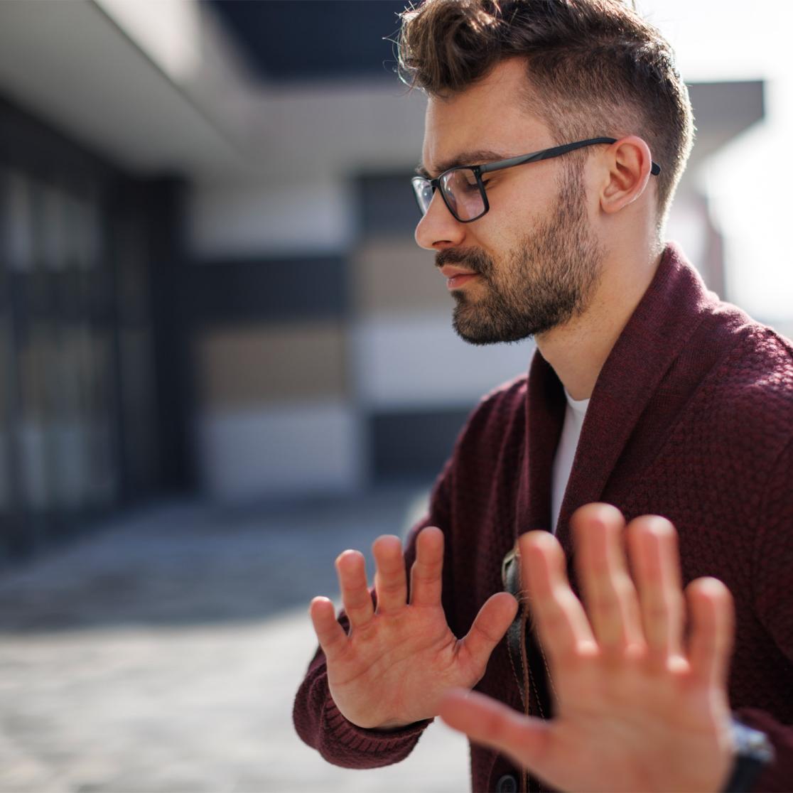 Male person with glasses setting boundaries by using his hands to push someone away