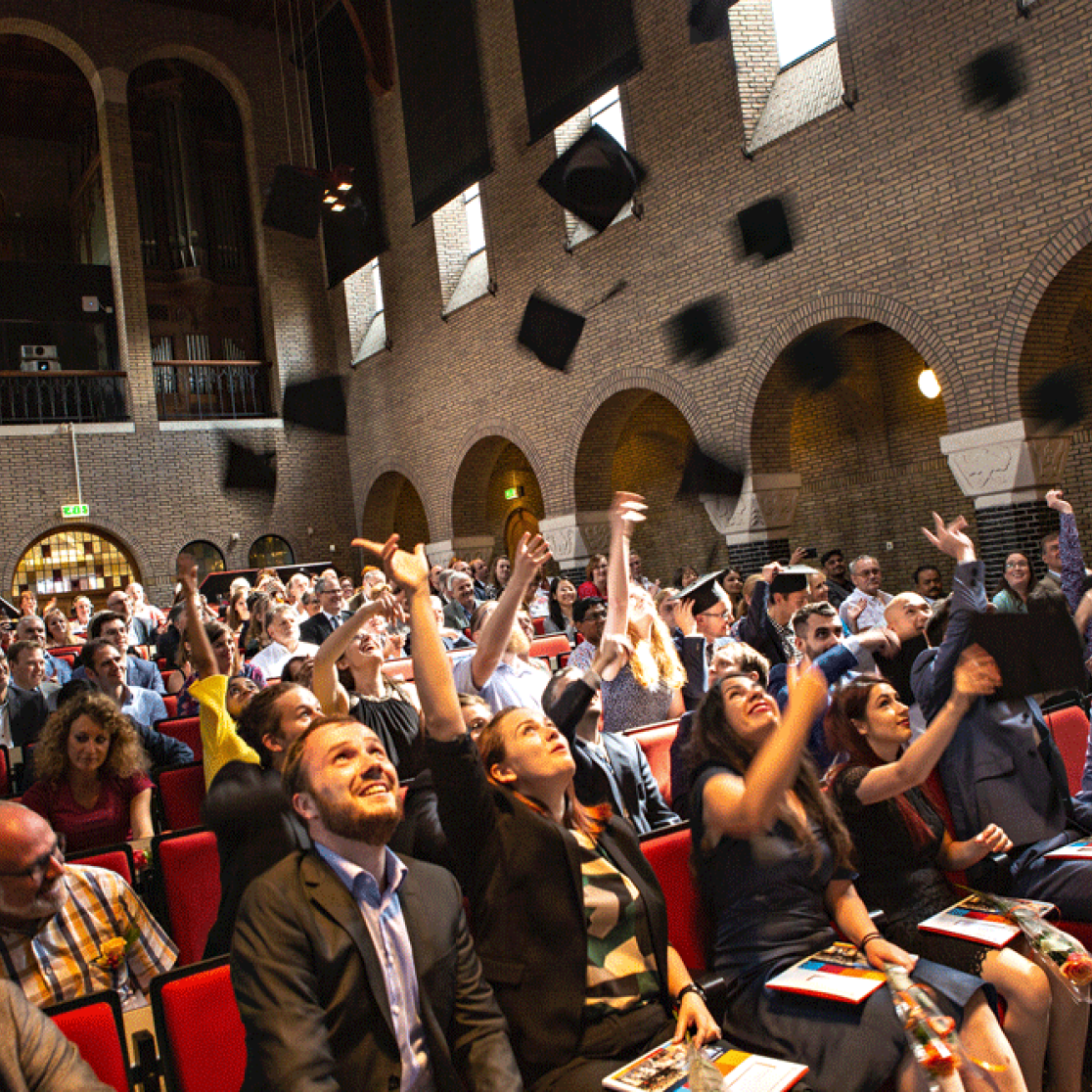 Student throwing caps in the air during graduation ceremony