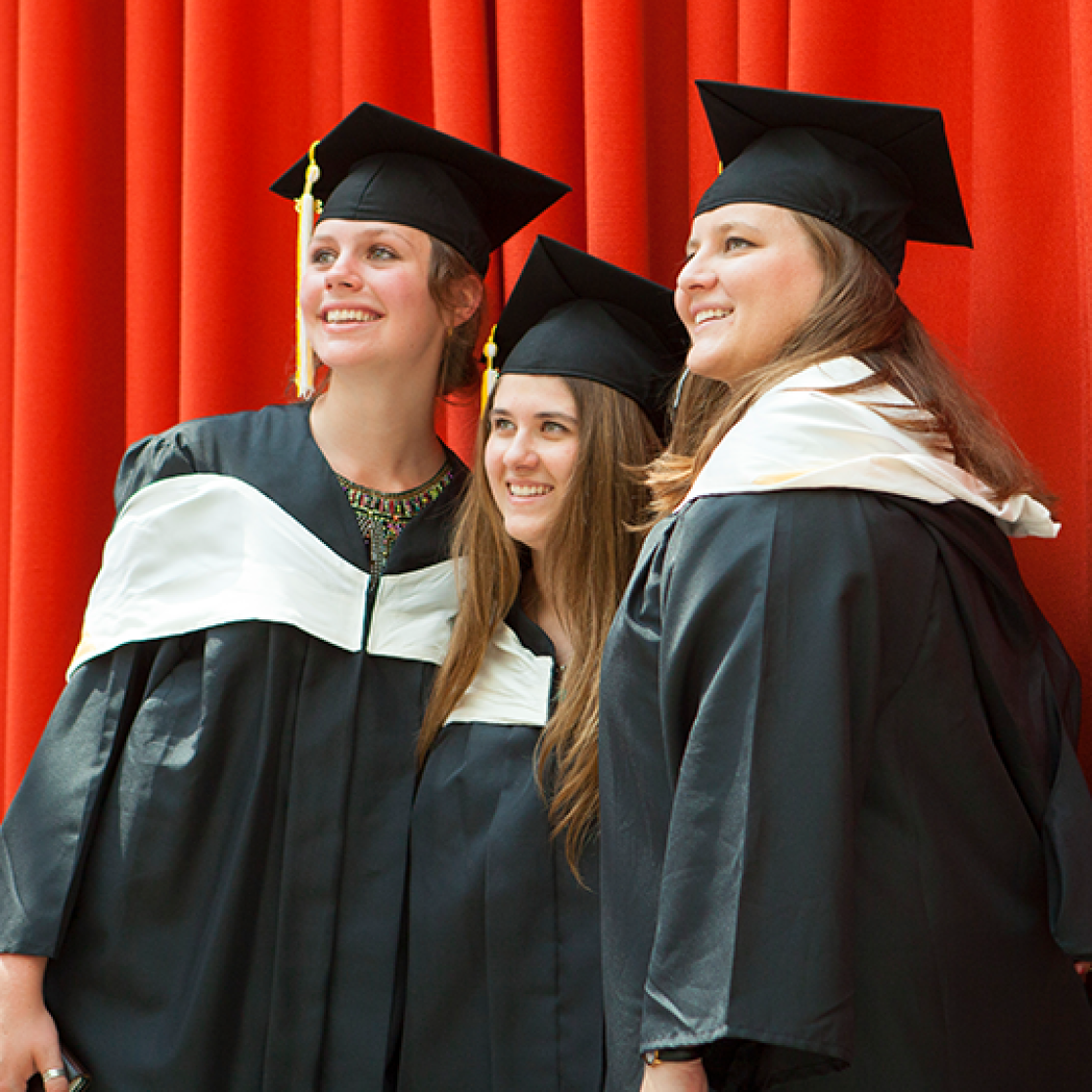 Graduates standing in front of red curtain