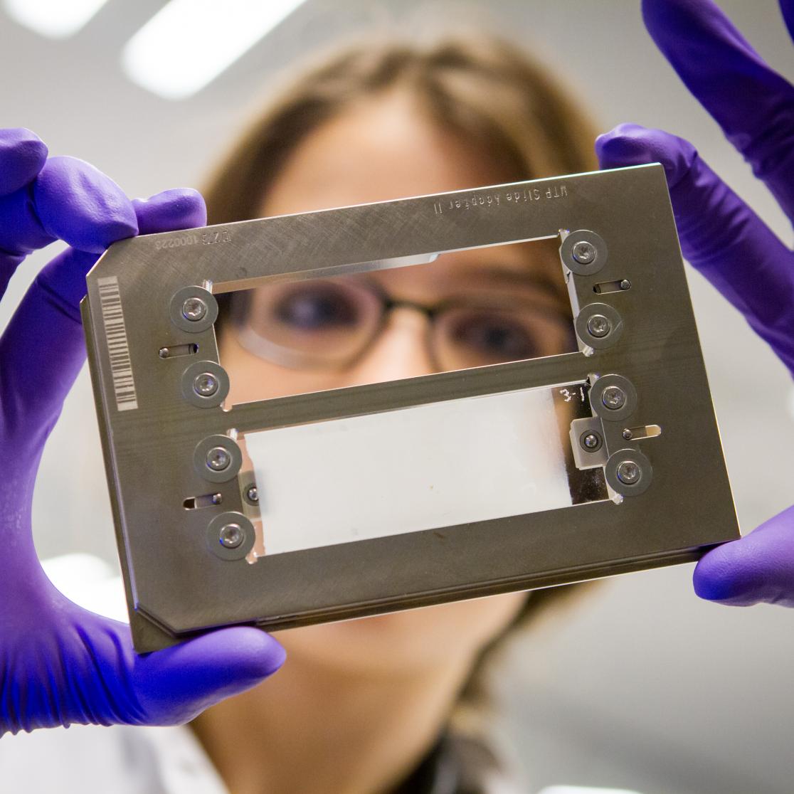 Girl with purple gloves holding piece of machine
