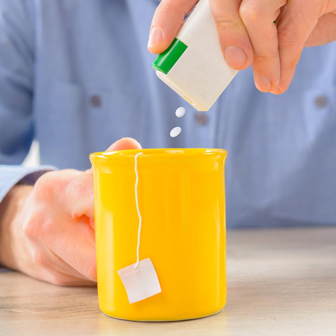 Person adding synthetic sweeteners to his tea