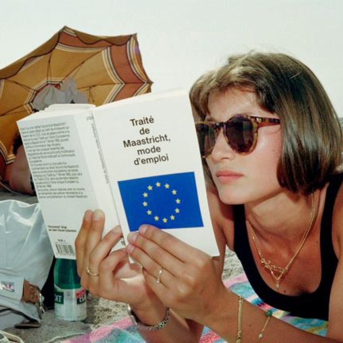 Woman on beach reading the Maastricht Treaty