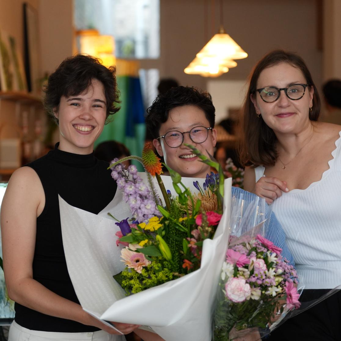 PhD candidate standing with flowers alongside paranymphs
