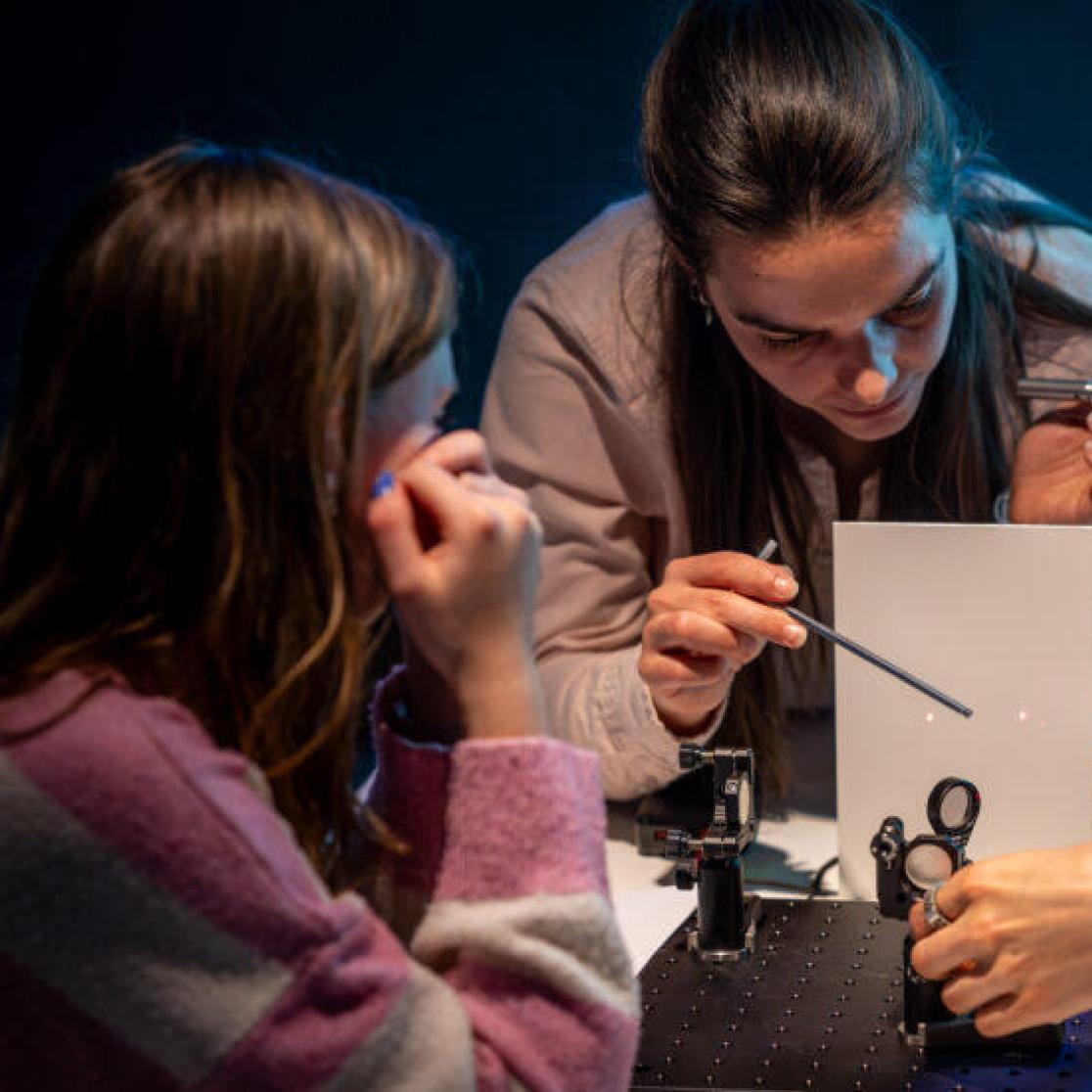 Emma Prins explaining a laser experiment to high school students