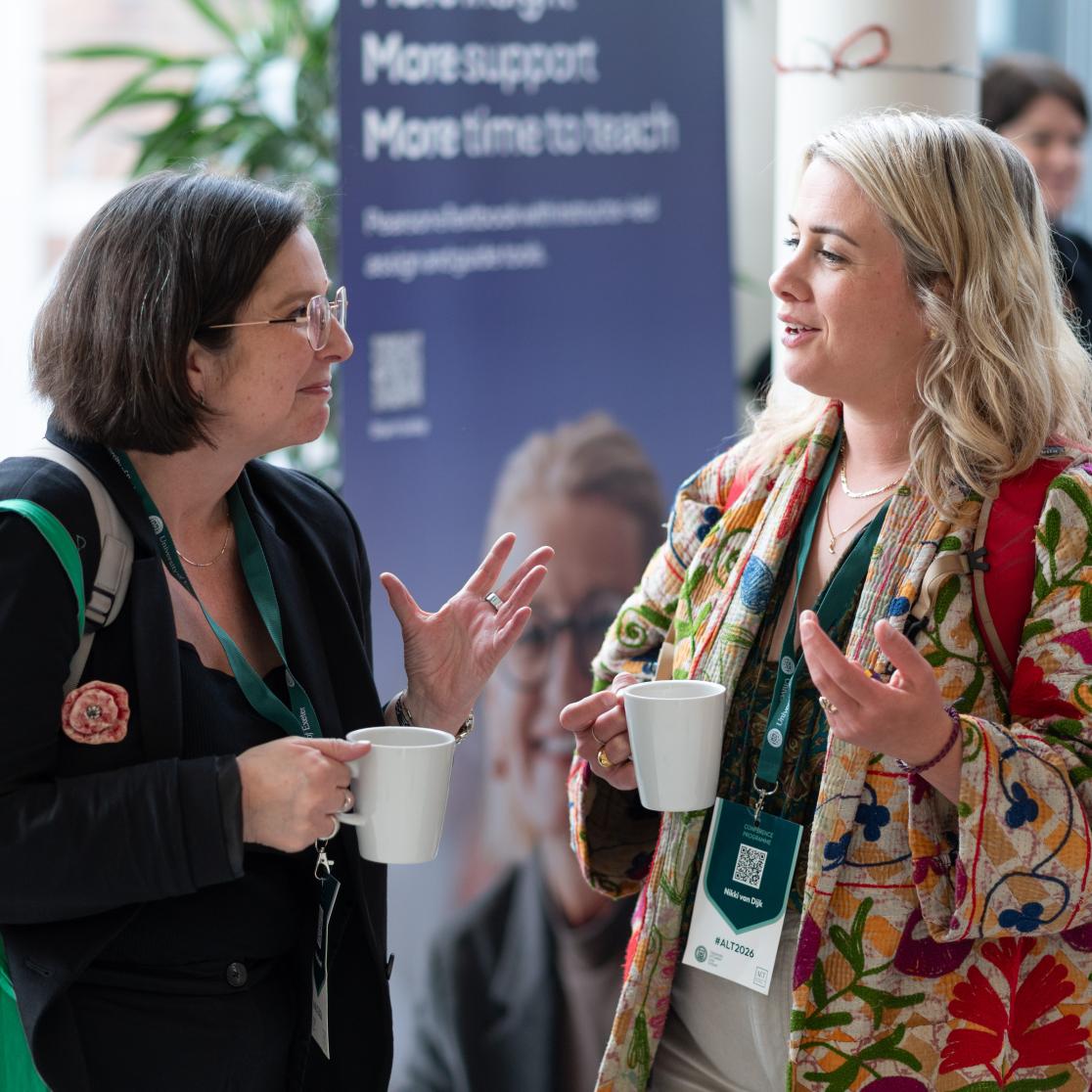 two participants at a conference talking over a cup of coffee