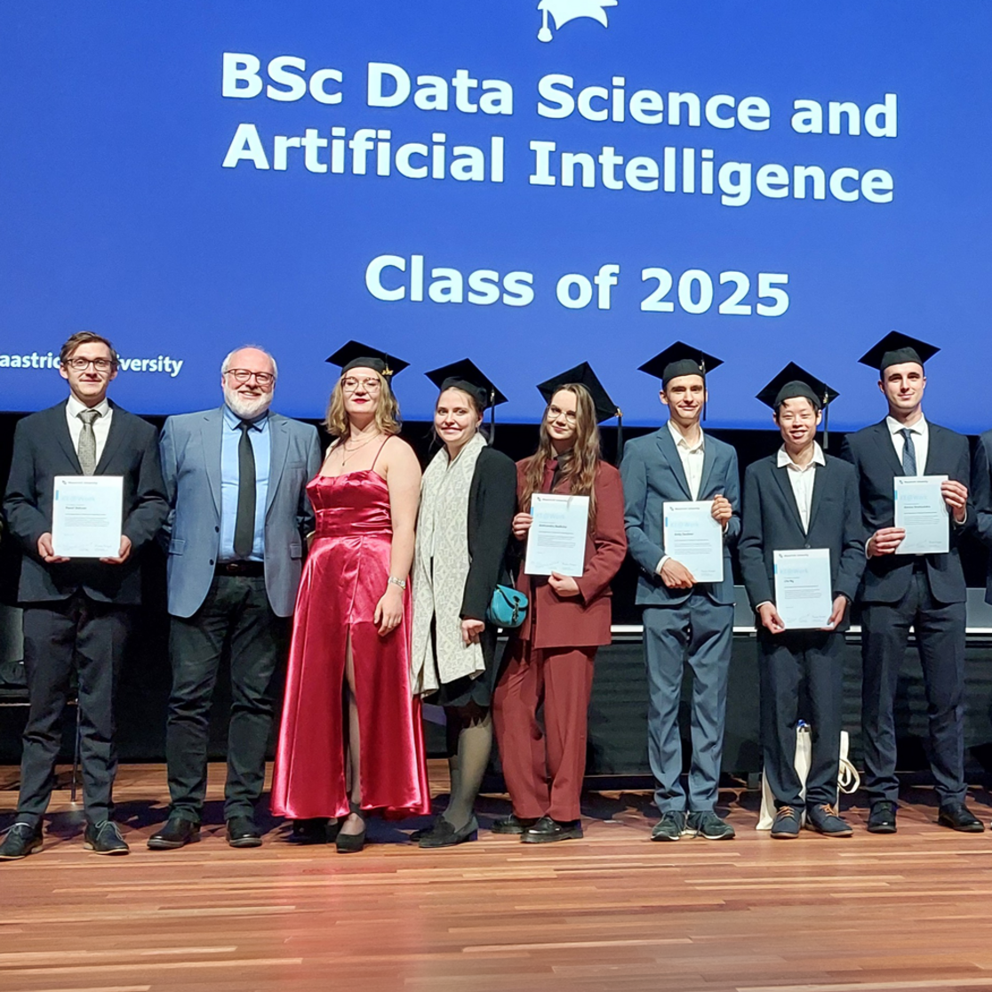 Students posing with professor at graduation ceremony on stage