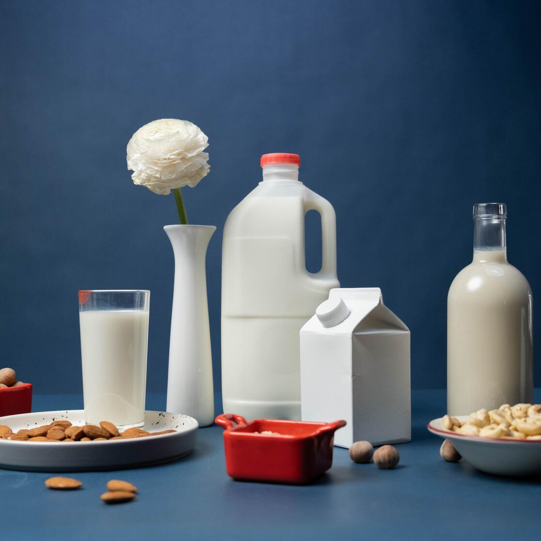 Still life of assorted vegan nut milks with nuts and decorative flower in studio