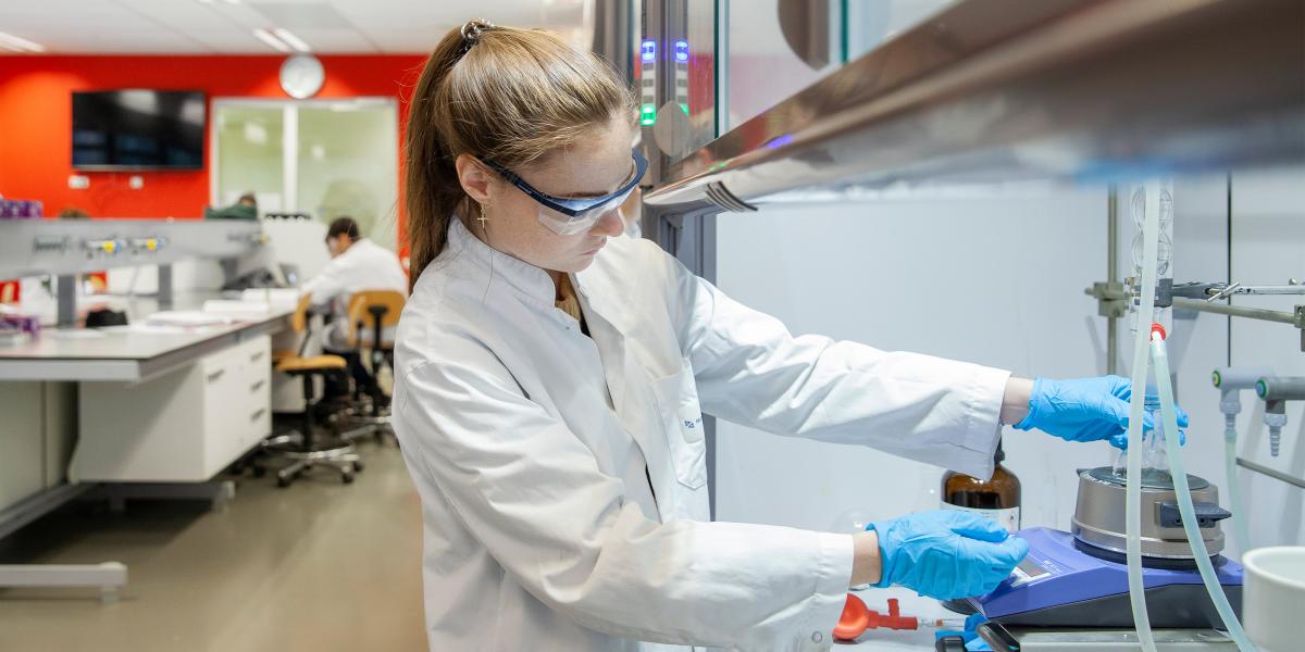University student in a lab coat conducting an experiment