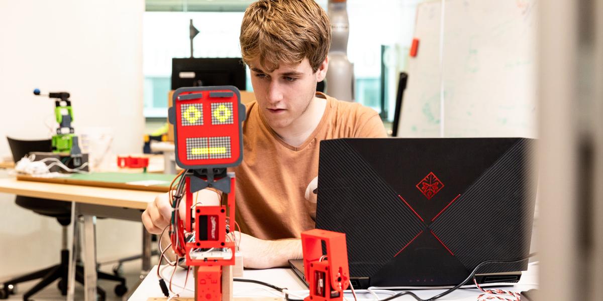 University student working on a robotics project with a laptop