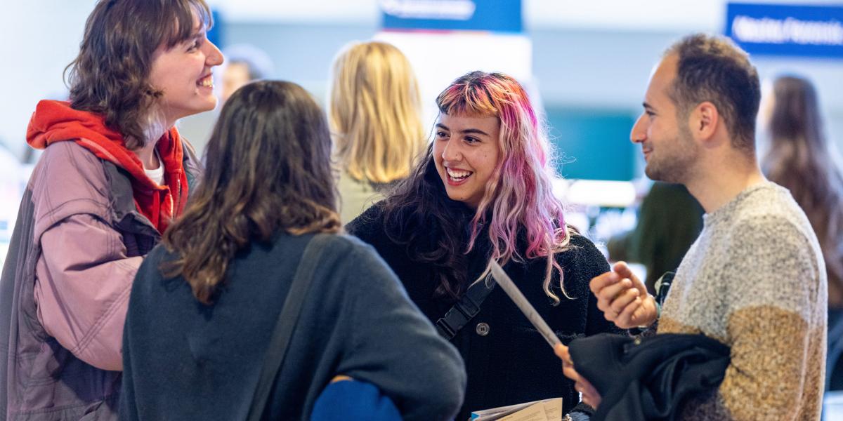 4 people in a conversation and smiling