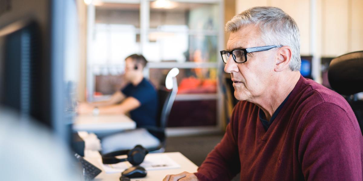Elderly male with glasses working at a computer