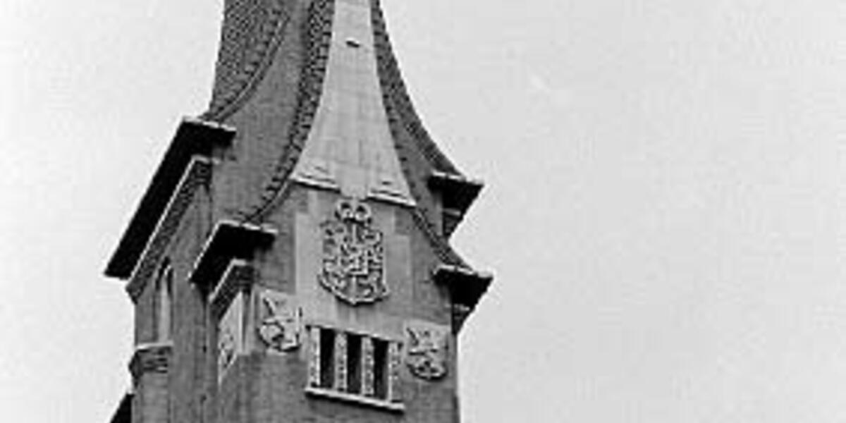 Zwart-wit foto van het monumentale faculteitsgebouw aan de Bouillonstraat in Maastricht, met een hoge, smalle toren met spits