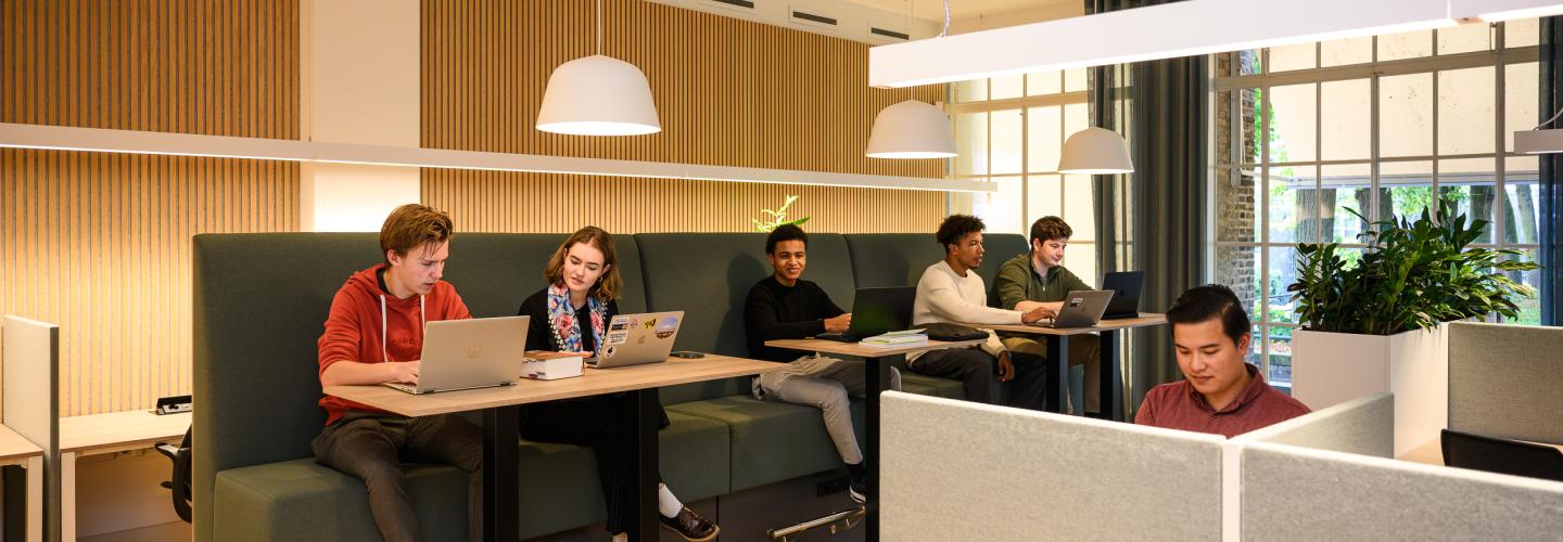 Students working with focus at both individual and shared workspaces in the faculty’s learning space.