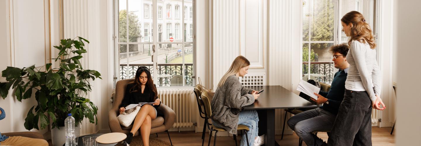 Studenten ontspannen en studeren in een lichte en elegante common room met uitzicht op de binnenstad van Maastricht.