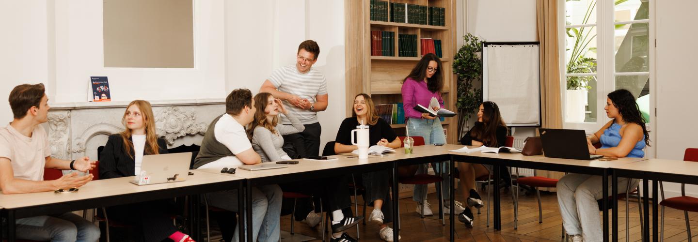 Students are seated in the Spiegelzaal of the faculty in an informal setup, where they are laughing, discussing and presenting together.