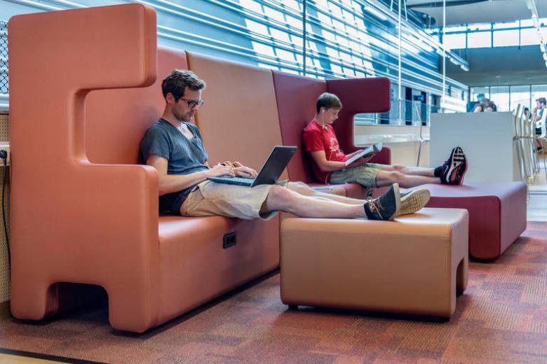 Students studying with laptops on lap at Maastricht University sports centre