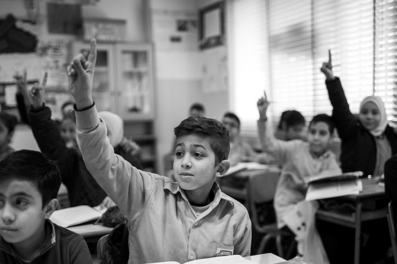 A boy raising his hand in a classroom