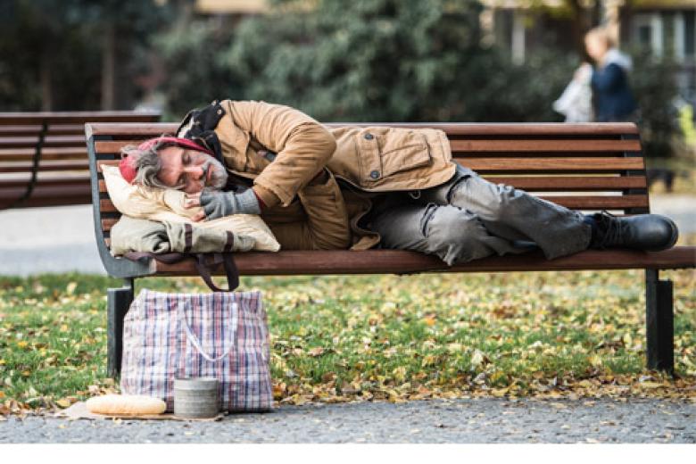 Homeless man lying on a bench in the park