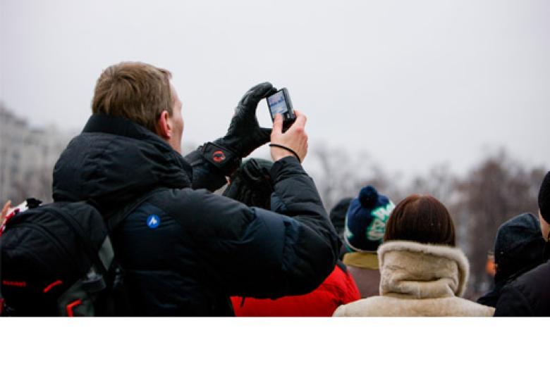 Photo: young man is filming a demonstration with his mobile phone
