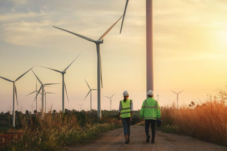 two people walking towards wind turbines