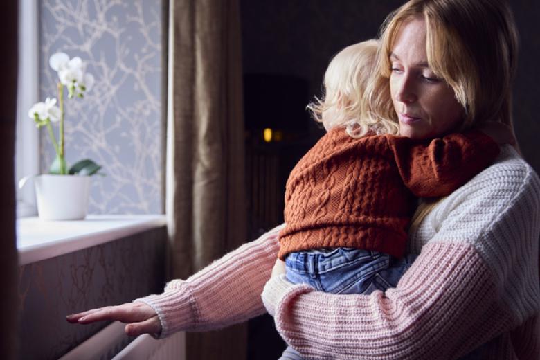 Woman in sweater holding child touching a heater