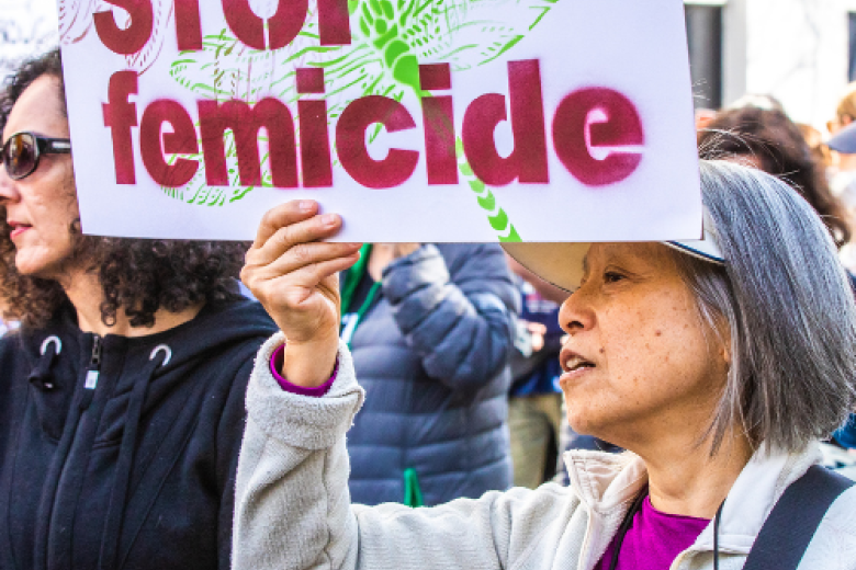 Woman holding a sign that says 'stop femicide'
