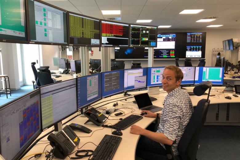 Jacco de Vries in a control room full of tv-screens at het LHCB laboratory at CERN