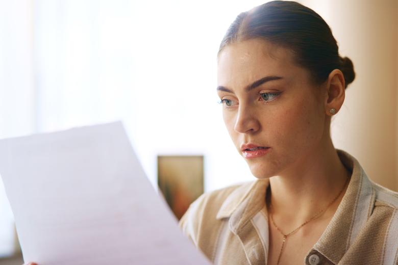 Young woman looking at a document with disbelief