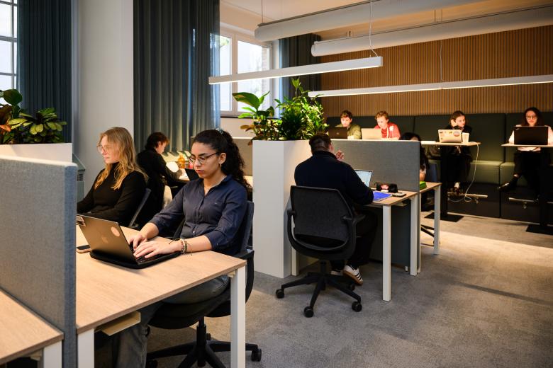 Students working quietly at individual desks and group benches in the faculty’s learning space.