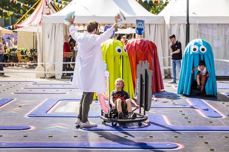  Een levensgrote Pacman-achtige game waar kinderen in hartvormige wagentjes rondrijden op een baan op Expeditie Next