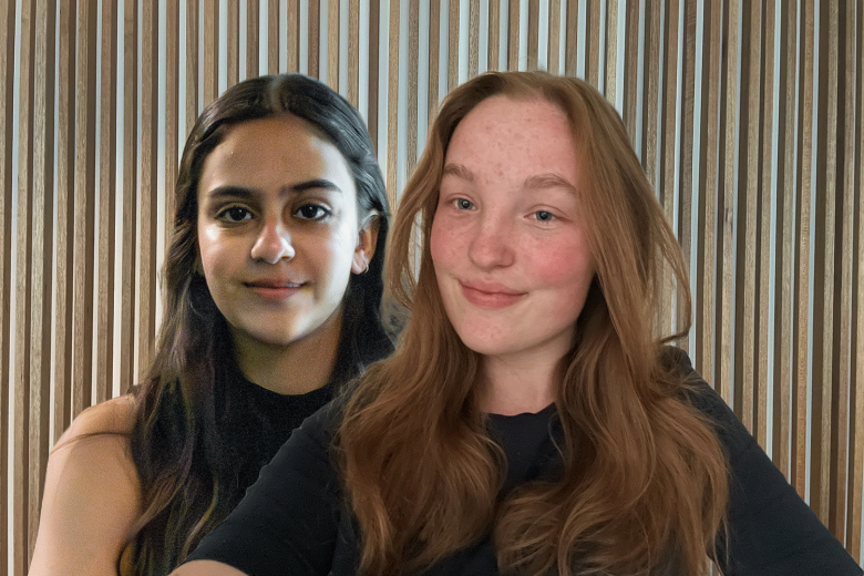 Two female students in front of wood panel wall