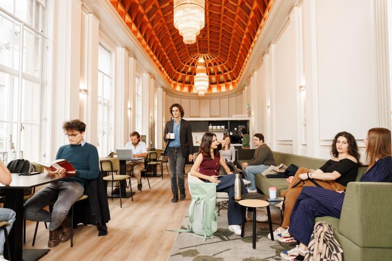 Studenten ontspannen, werken en praten met elkaar in een stijlvolle gemeenschappelijke ruimte met hoge plafonds en kroonluchters.