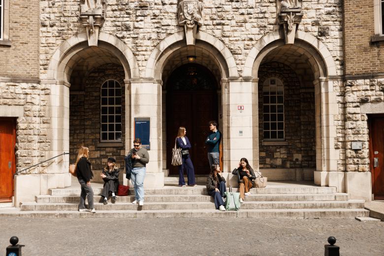 Students sitting and chatting on the steps of the historic entrance of the Faculty of Law on Lenculenstraat in Maastricht.