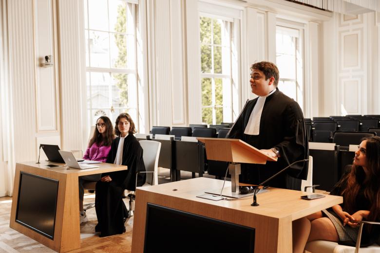 Studenten oefenen een rechtszaak in toga tijdens een moot court-sessie aan de rechtenfaculteit van Maastricht University, in een lichte zaal met grote ramen.