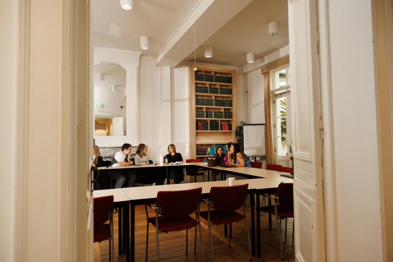 View through a doorway into a tutorial group in the Faculty of Law’s Spiegelzaal, featuring bookshelves, a flipchart, and a classic interior.